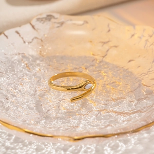 Detail of 18K gold snake-style ring with white marquise stone on textured glass dish