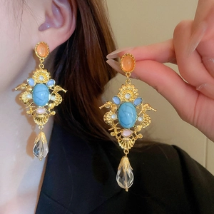 Detail of vintage palace style earrings with colorful gemstones and teardrop pendant