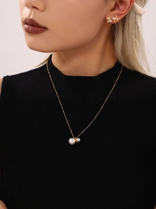 Detail of gold necklace and bow earrings set with white pearls and micro-pave crystals