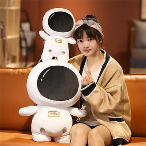 Detailed comparison of large and small astronaut plush toys on a warm leather sofa
