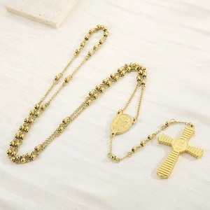 Macro detail of gold-plated rosary necklace featuring a crucifix and Saint medal