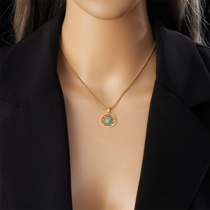 Detail of a gold-plated stainless steel necklace with a sunburst turquoise pendant on a model