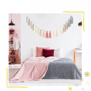Detail of pink, beige and grey tassel wood bead garland hanging on a bedroom wall
