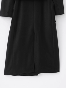 Detailed close-up of the black wool coat back hem with center seam and twill texture