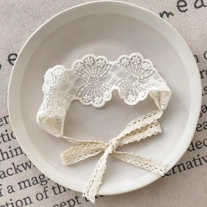 Détail de la broderie florale en dentelle blanche sur un bandeau doux pour bébé fille