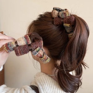 Detail of a vintage chunky knit bow hair claw clip styled on a low ponytail