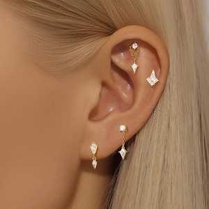 Gros plan de boucles d'oreilles en or et diamants portées sur le cartilage féminin