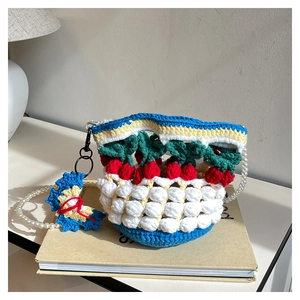 Close-up of handmade crochet cherry bucket bag with pearl strap on vintage books