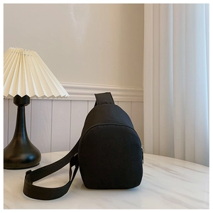 Minimalist black kids chest bag on white marble surface with soft interior lighting