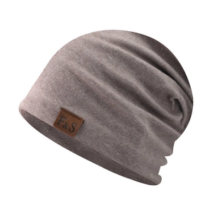Detailed view of beige knit beanie showing soft ribbed texture and leather logo patch