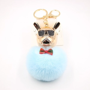 Dettaglio portachiavi con pompon blu, ciondolo bulldog dorato e occhiali da sole