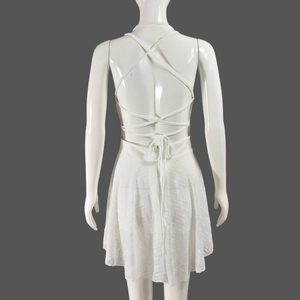 Détail de la robe dos nu en dentelle blanche montrant la texture ajourée et le lien à nouer