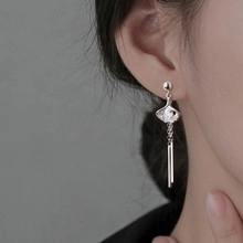 Close-up of silver ginkgo leaf tassel earrings worn on ear with elegant hanging chains