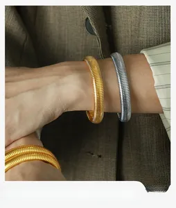 Close-up of ribbed snake bone bracelet in gold and silver on a suited wrist