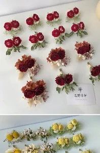 Detail of handcrafted wedding corsage set with red roses and white berries on white background