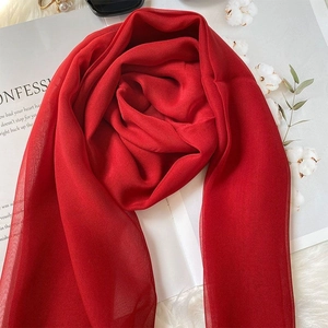 Close-up of lightweight vibrant red silk shawl draped over a magazine and cotton branches
