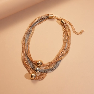 Detail of layered gold and silver mixed metal chain necklace with three round bead pendants