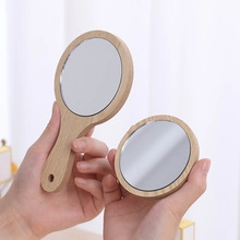 Detailed view of natural wooden hand-held vanity mirror and small round pocket mirror