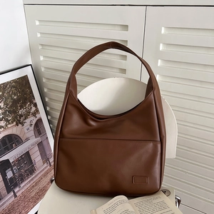 Detailansicht der braunen Schultertasche aus Kunstleder auf einem Stuhl in Wohnumgebung