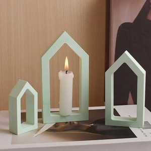 Trio of sage green hollow house candle holders in varying sizes on a magazine