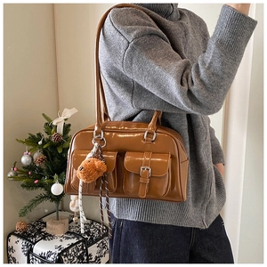 Detail of vintage brown pillow bag featuring double front buckle pockets and plush charm