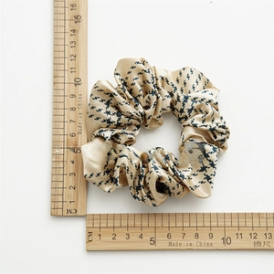 Detailed size measurement of a champagne satin scrunchie with houndstooth patterns