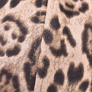 Detailed macro view of the leopard print fabric texture and reinforced stitching line