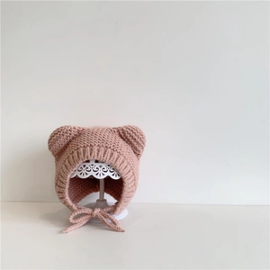 Detail showing pink knitted baby hat with bear ears and soft chin straps