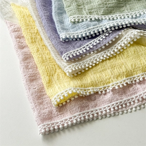 Detailed close-up of textured lace headbands with pom-pom trim in various pastel colors