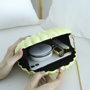 Acrylic yellow shell clutch bag with gold chain strap showing internal storage capacity