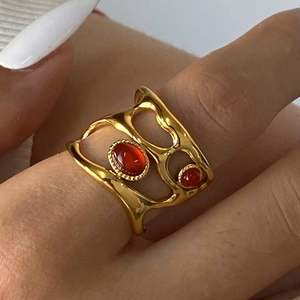 Detail of an irregular 18k gold plated ring with dual red agate stones on a hand