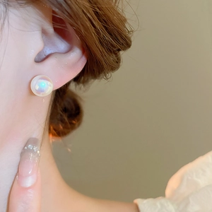Close-up of elegant gold-plated mermaid pearl earrings with iridescent luster on ear