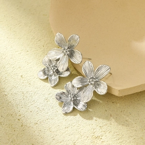 French vintage silver flower stud earrings with textured petals on a stone surface