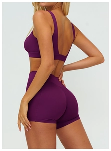 Rear view of dark purple yoga set featuring a backless sports bra and high-waist biker shorts