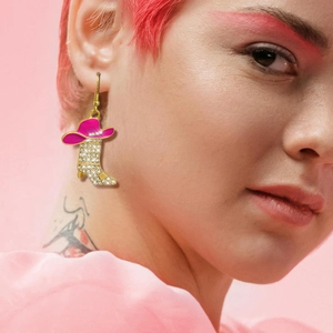 Detailed view of pink cowboy hat and boot earrings with zircon stones on female model