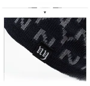 Detail of navy knit beanie showing grey jacquard patterns and embroidered logo label