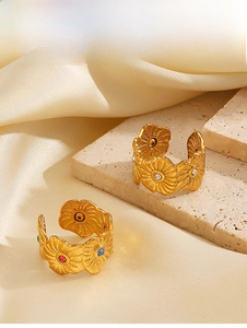 Detail of gold sunflower rings with colorful rhinestones on silk and stone background