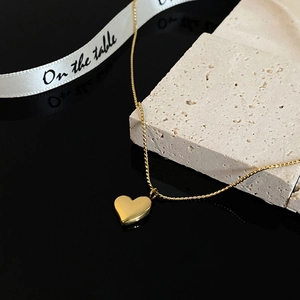 Polished 18k gold heart pendant necklace on minimalist chain with stone prop display