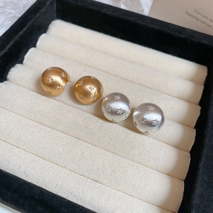 Close-up of 10mm 18k gold plated ball earrings with brushed texture and zircon star detail