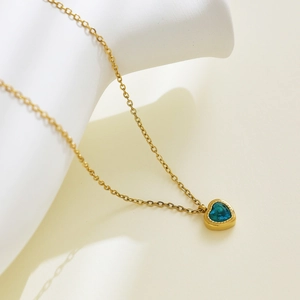 Detail of 18k gold plated necklace with a heart-shaped blue zircon pendant on stone