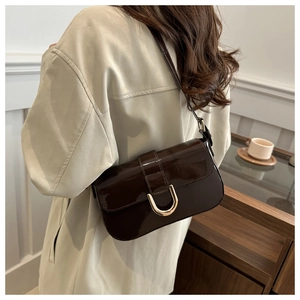 Close-up of a vintage dark brown patent leather shoulder bag with a metal horseshoe buckle
