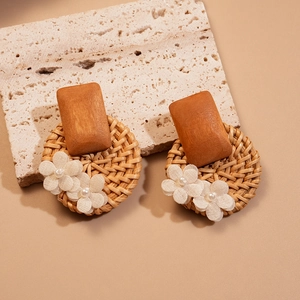Bohemian rattan earrings with wood square and white fabric flowers on stone background