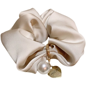 Elegant beige satin scrunchie with a gold heart charm and pearl pendant detail
