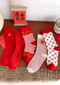 Detailed view of festive red cotton socks with embroidery and heart patterns on wood