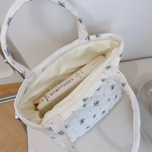 Detail view of the quilted cotton floral tote bag showing its blue floral pattern and interior