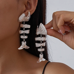 Exaggerated silver fishbone drop earrings with textured metal finish on model