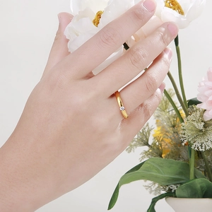 Minimalist gold stainless steel ring with zircon gemstone worn on finger near white flowers