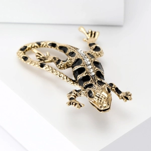 Detailed close-up of a golden lizard brooch with black enamel and sparkling rhinestones