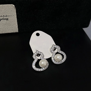 Detail of silver gourd earrings with cubic zirconia edges and white pearls on card
