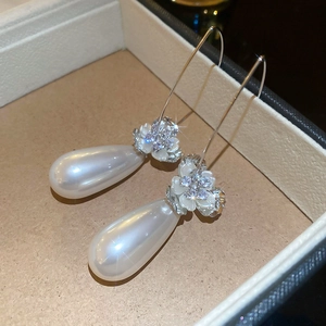 Détail macro de boucles d'oreilles perles goutte avec fleurs en zircon sur écrin